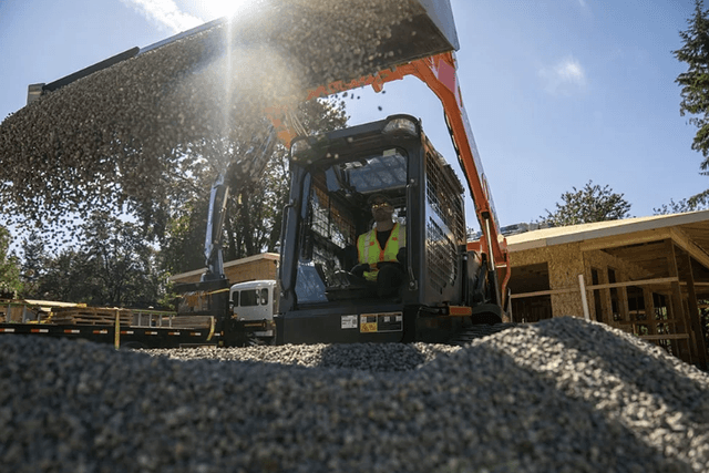 Close-up of track loader dumping fravel