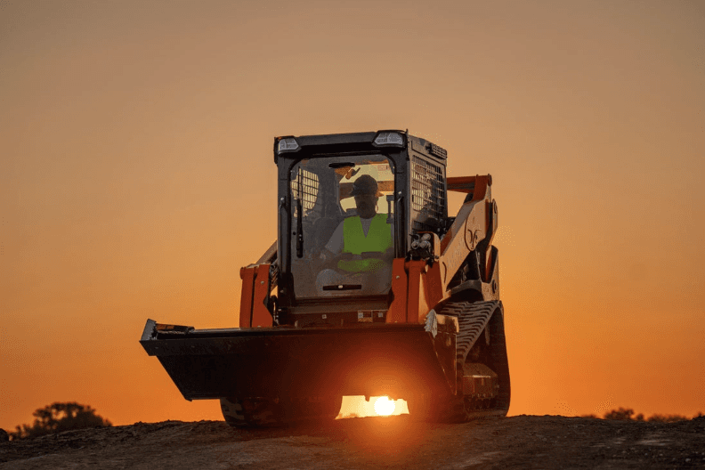 Track Loader driving with an orange sunset