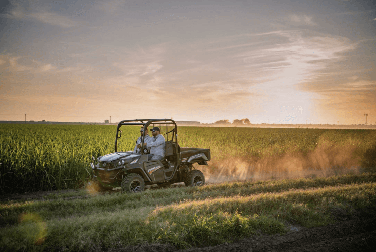 RTV driving down a dirt road in front of a sunset