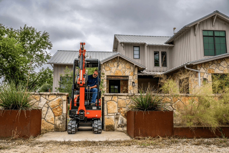 Man driving a Compact Excavator through a narrow gate
