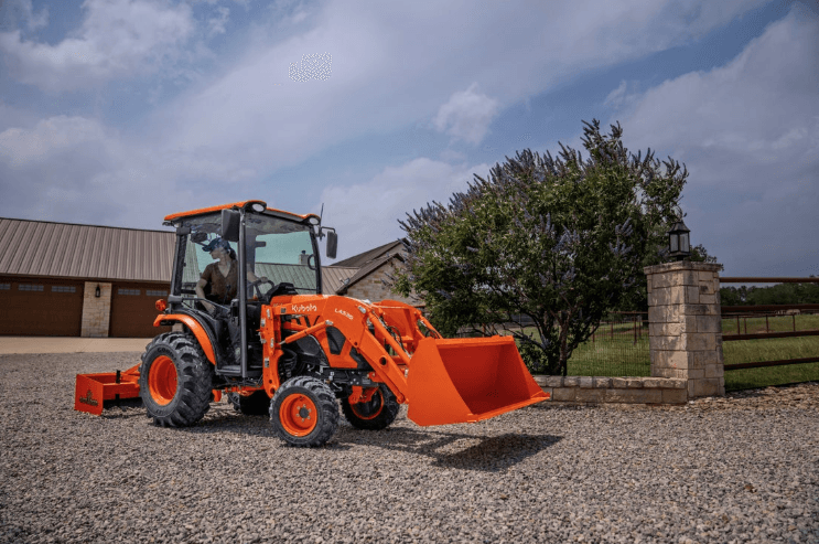 Woman using tractor box blade to level driveway